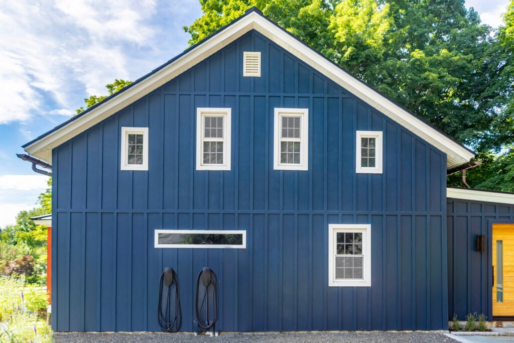 Dark blue board-and-batten siding with white window trim on a gabled exterior