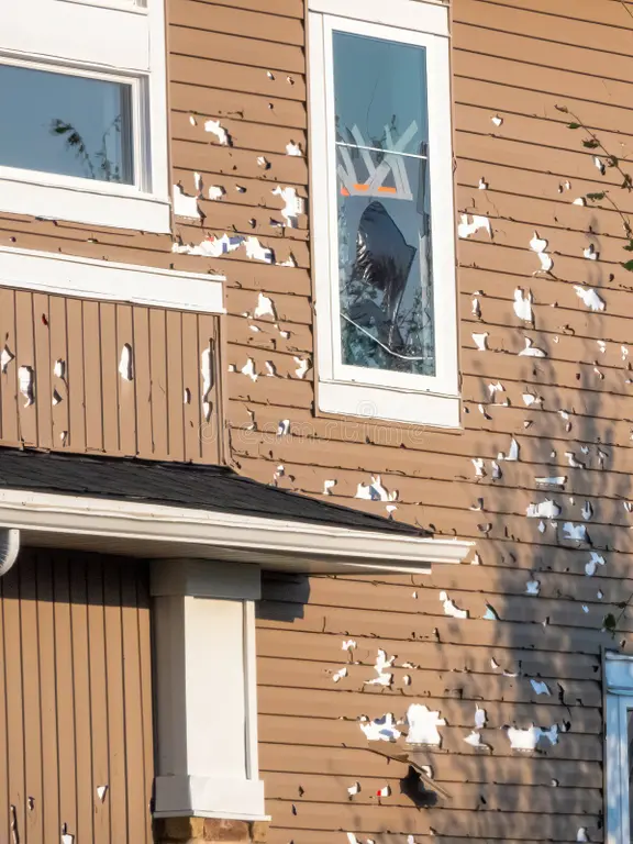Cracked and damaged vinyl siding after hail