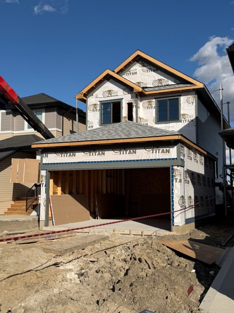 Front view of an Alpine Park Calgary new-build home with exposed house wrap on the upper level and garage before vinyl siding completion.