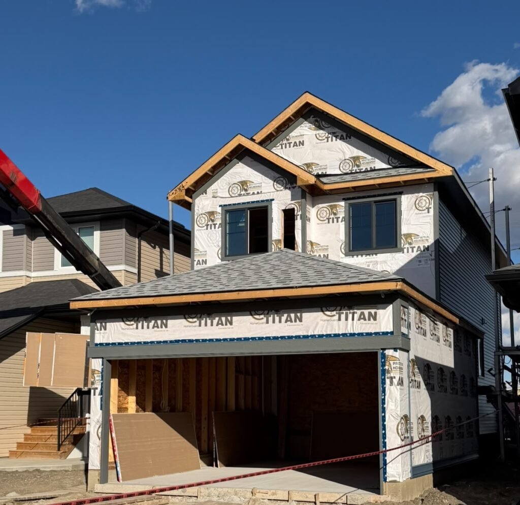 Front view of an Alpine Park Calgary new-build home with exposed house wrap on the upper level and garage before vinyl siding completion.