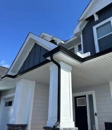 Black gutters and downspouts along a residential roofline