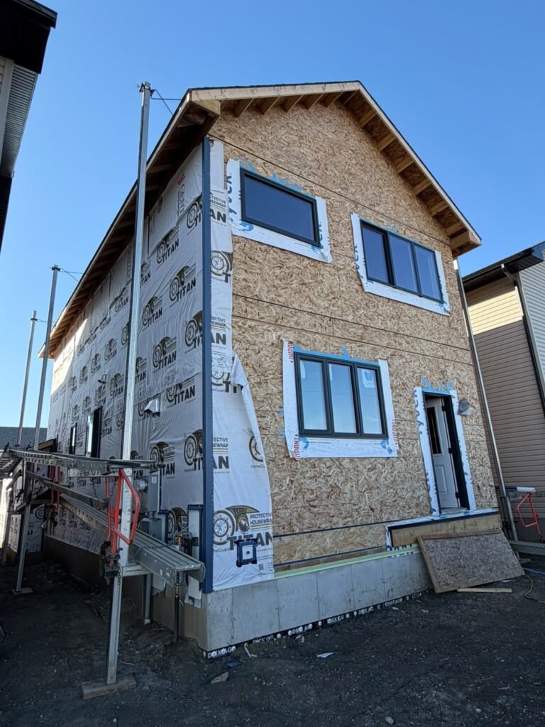 New-build home in Alpine Park SE Calgary with exposed OSB sheathing and house wrap before vinyl siding installation.